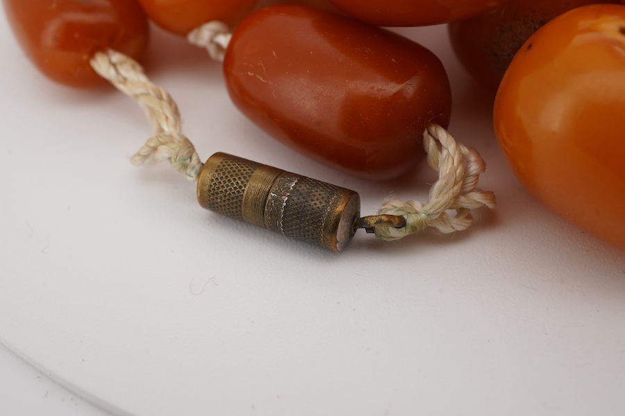 A single strand oval and barrel shaped amber bead necklace, 90cm, gross weight 102 grams. Condition - poor to fair